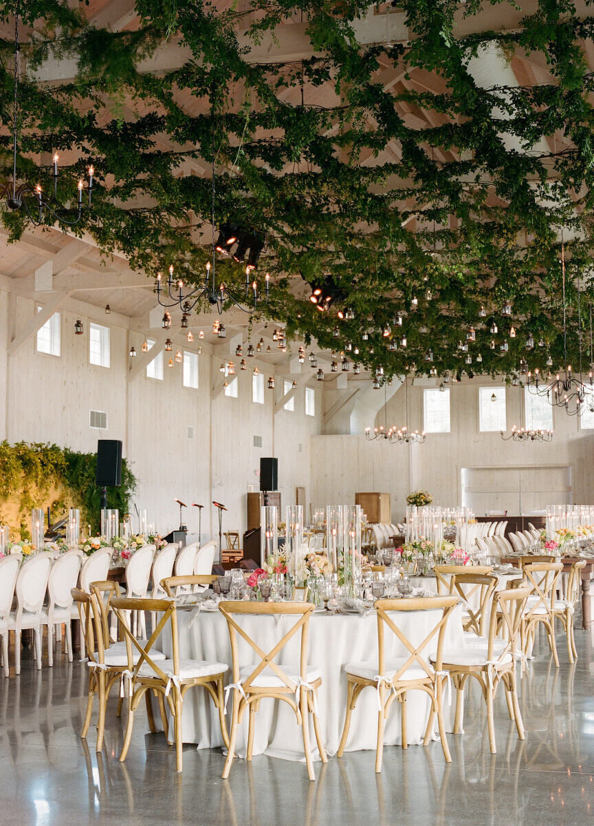 At this Glenmere Mansion wedding, the reception barn was decorated with a lattice of greenery hanging overhead, and a mix of long and round tables decorated with peach and white centerpieces.