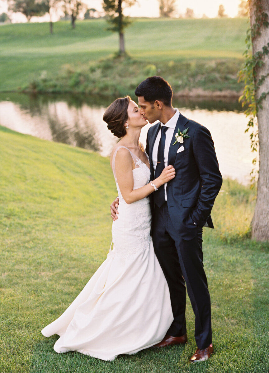 Golf Course Wedding Venues: A wedding couple kissing in front of a pond and golf course.