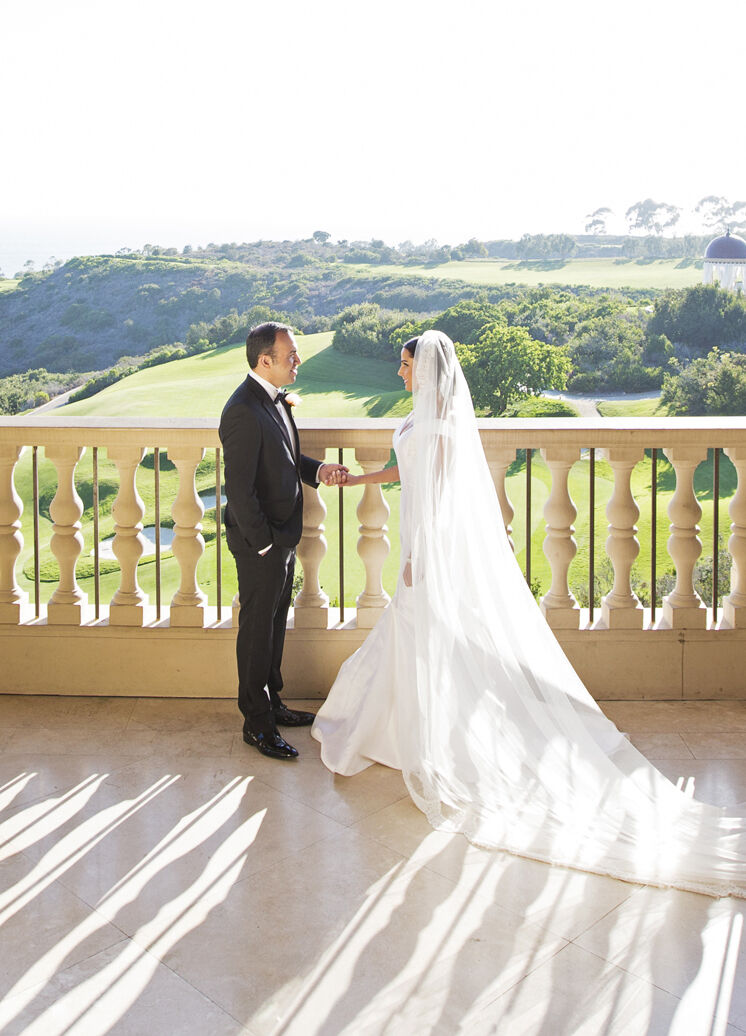 Golf Course Wedding Venues: A wedding couple on a balcony overlooking a sprawling golf course.