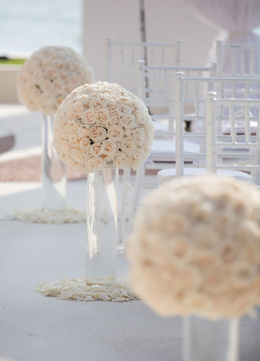 Grand Velas Riviera Nayarit: A series of tightly-packed white rose floral arrangements at the end of every other row in a wedding aisle.