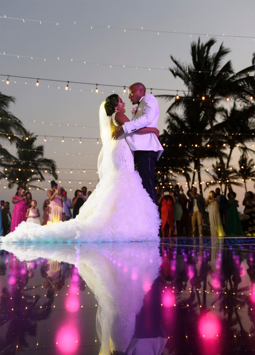 Grand Velas Riviera Nayarit: A bride and groom dance under string lights on a light-up dance floor in the early evening.