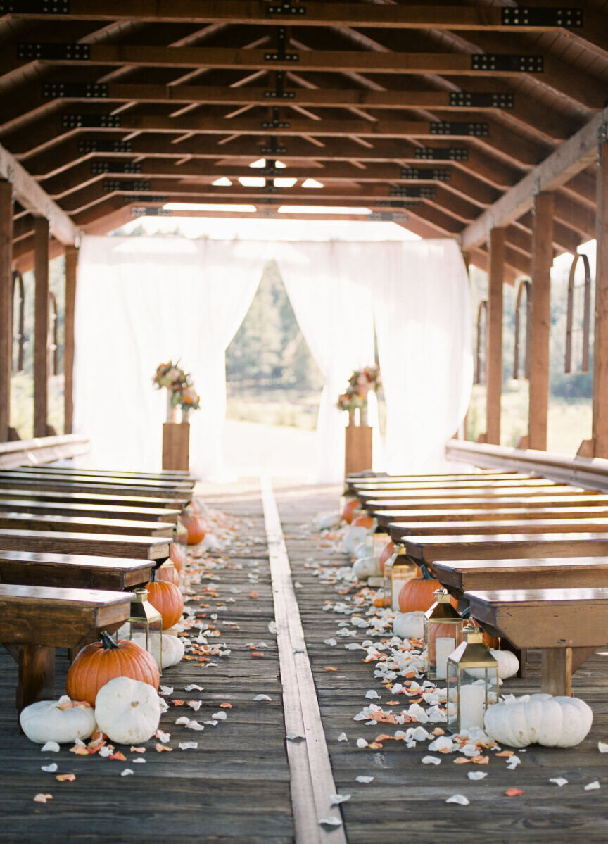 Holiday Wedding: Pumpkins lining the aisle of a wedding in an indoor-outdoor space.