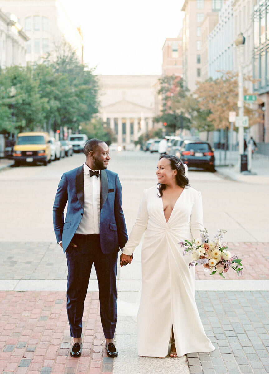 Holiday Wedding: Bride and groom smiling and looking into one another's eyes as they stand in the middle of the street.