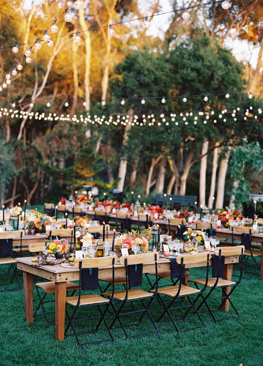 Holiday Wedding: Outdoor reception set-up with wooden chairs and tables, string lights and fall-inspired florals.