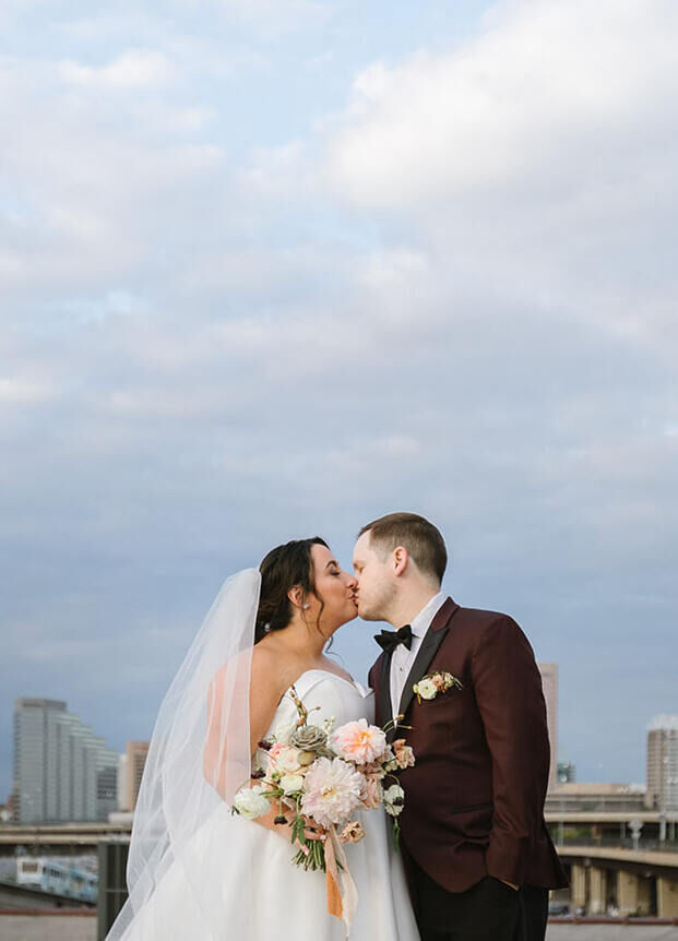 A bride and groom share a kiss on the roof of a building in Baltimore, where they had their industrial wedding.