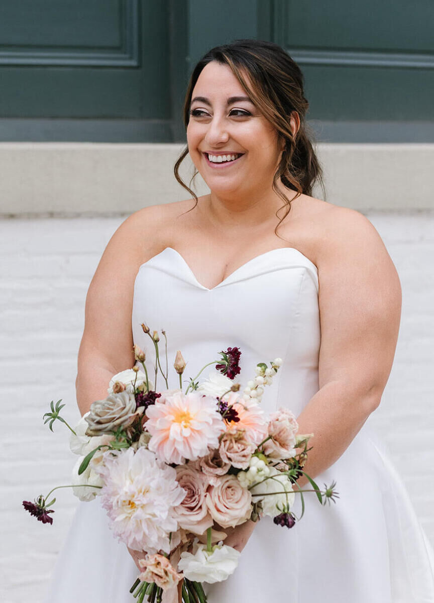 A smiling bride wears a natural face of makeup that accentuates her features at her industrial wedding.