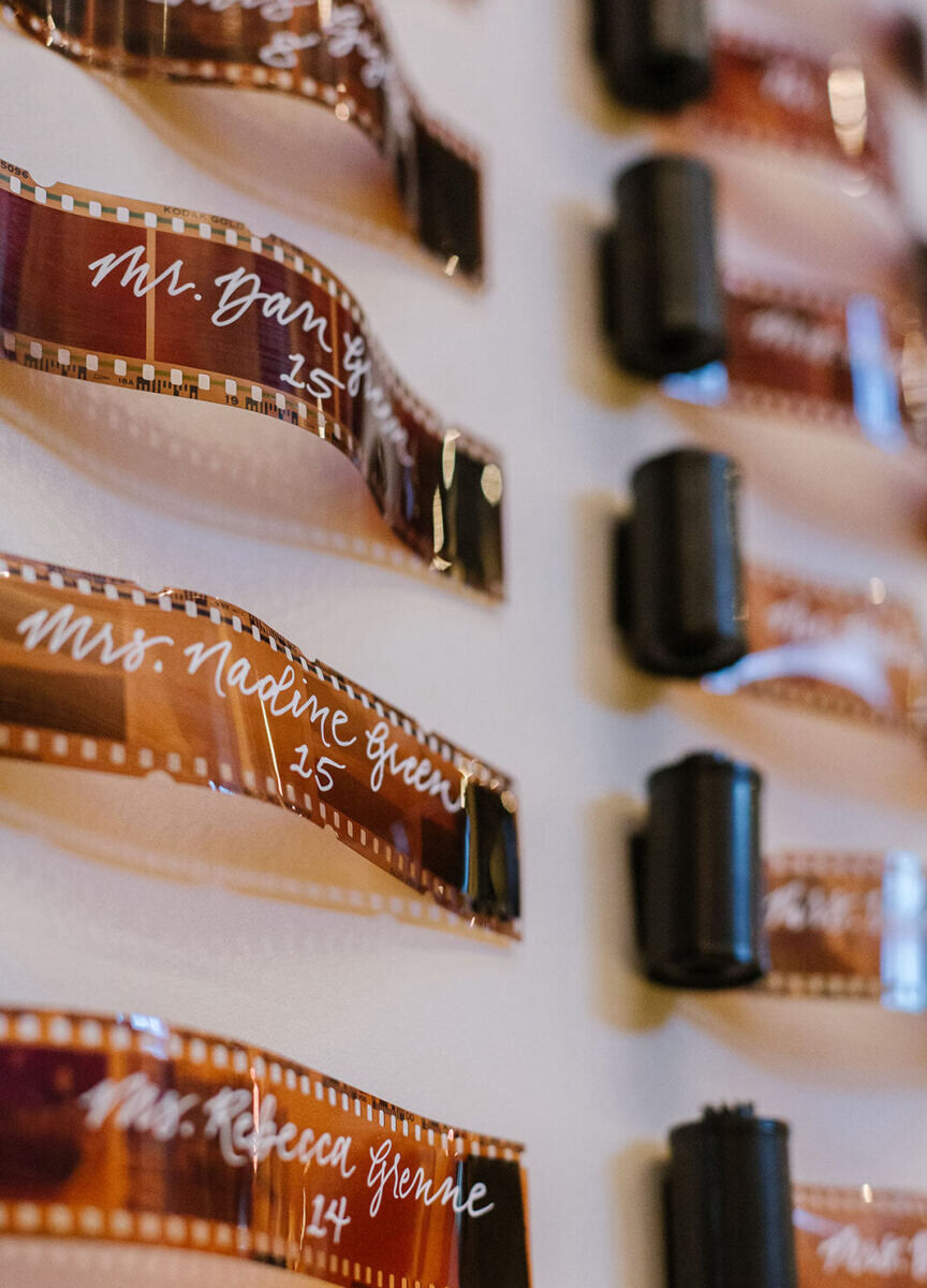 Calligraphed rolls of film, in matte black canisters, were installed as a unique seating display honoring the groom's photojournalistic background at his industrial wedding in Maryland.