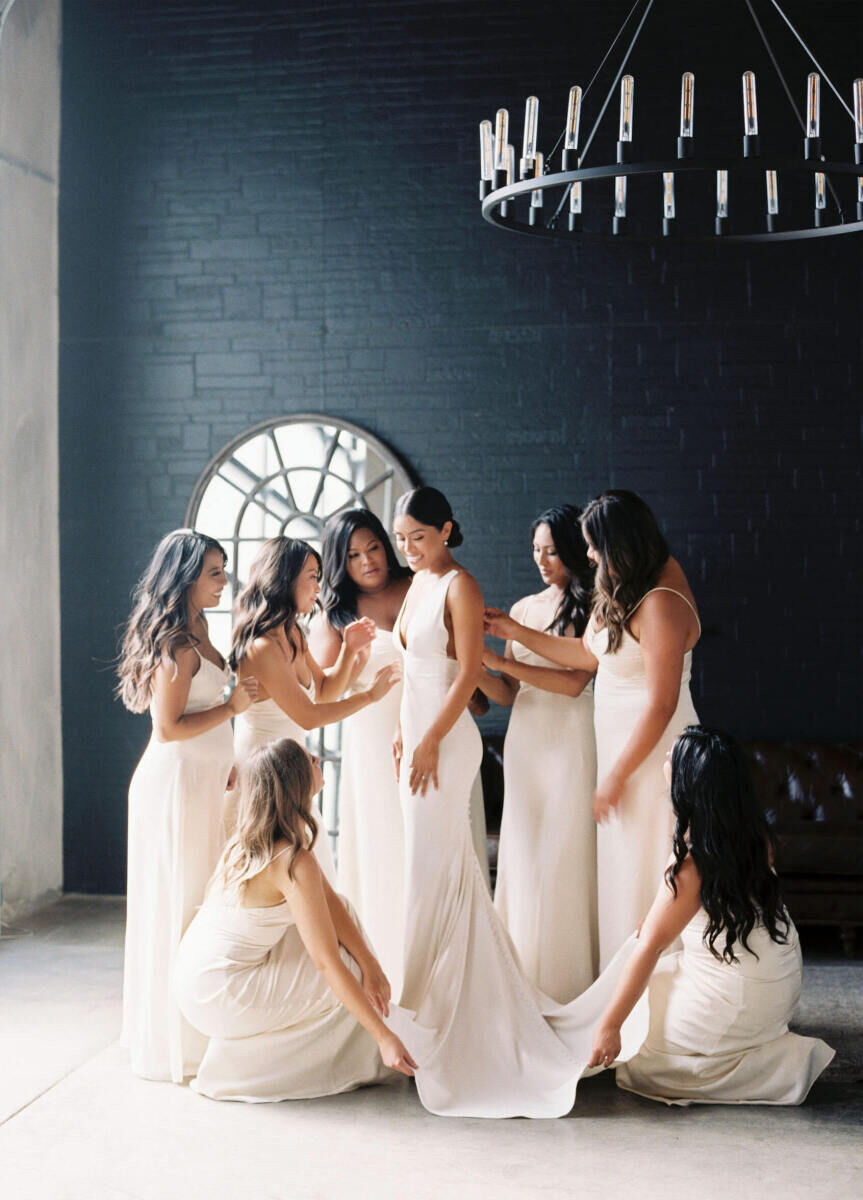 Industrial Wedding Venues: Bridesmaids lovingly adjusting a bride's wedding gown at Bloc.