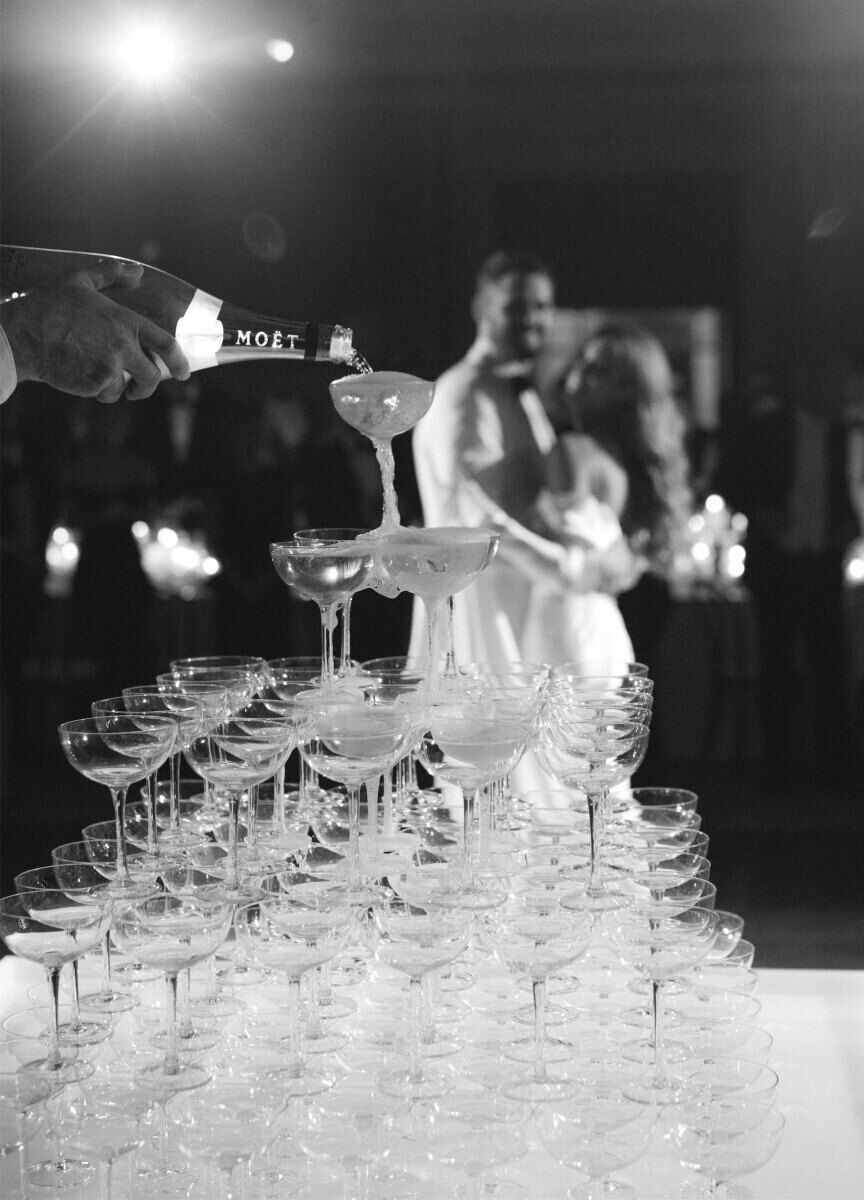 Kate Bock Kevin Love Wedding: A champagne tower with newlywed couple Kate Bock and Kevin Love dancing in the background.