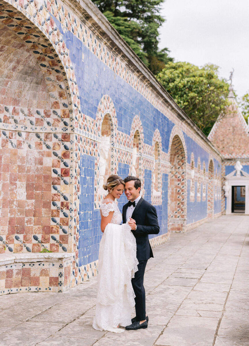 Latinx Heritage: A bride and groom embracing near a tiled outdoor archway in Lisbon, Portugal.