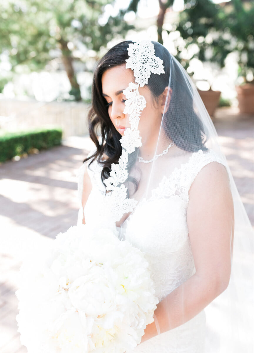 Latinx Heritage: An up-close image of a bride wearing a mantilla veil and holding a bouquet of white flowers.