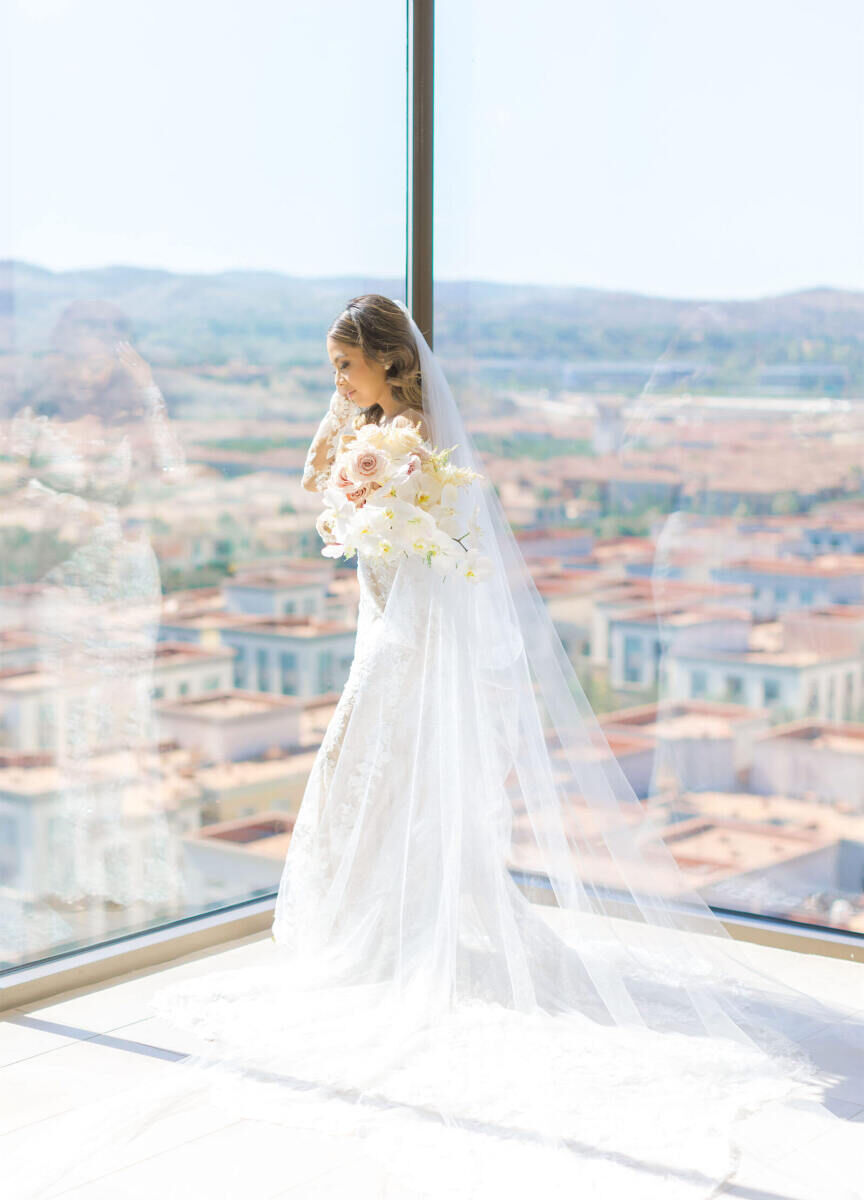 Marriott Weddings: A bride posing for a wedding portrait while looking through a glass-walled area in Orange County, California.