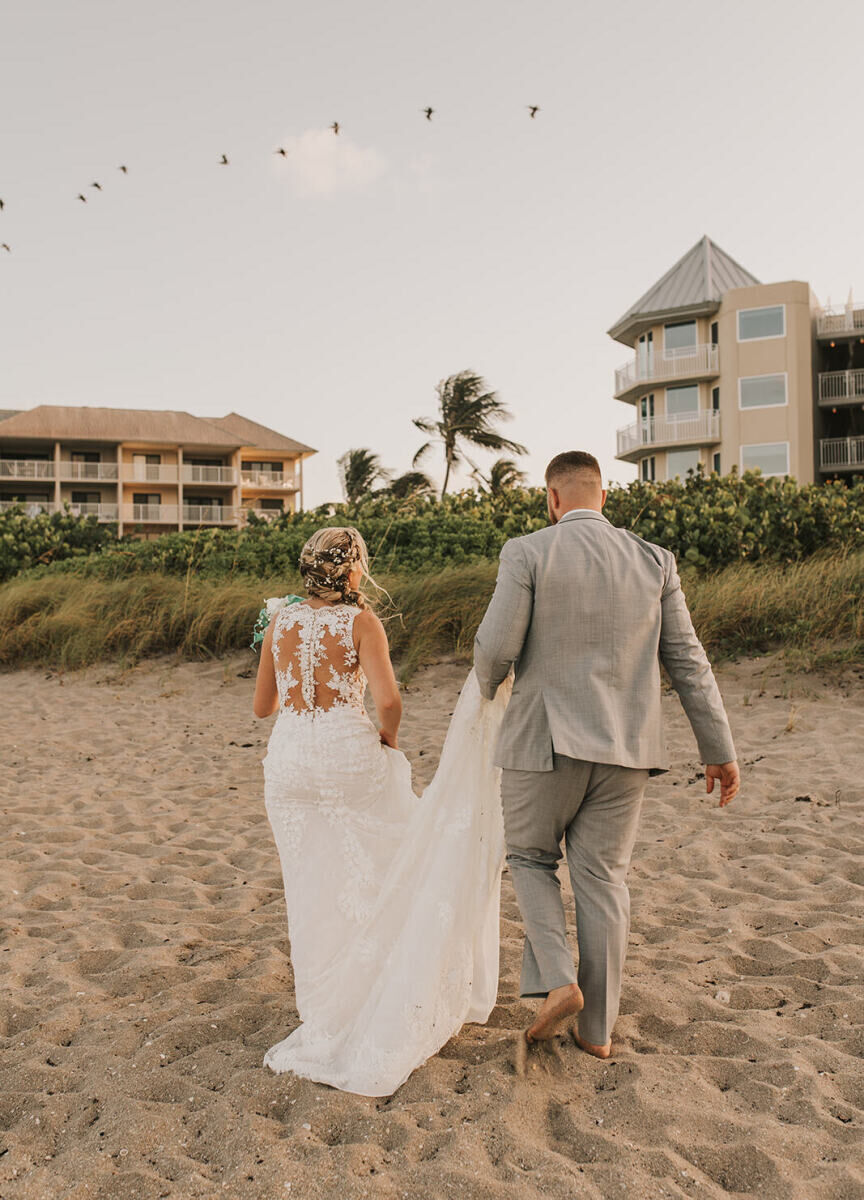 Marriott Weddings: A couple walking away from the beach while walking on the sand toward a resort in Florida.