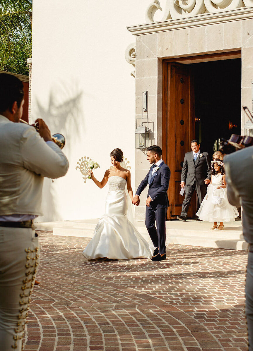 Mexican wedding: couple emerging from a church being serenaded by a mariachi band