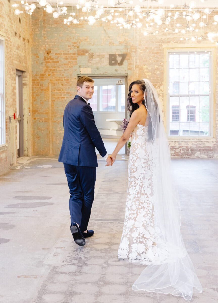 Best Places for a Minimalist Wedding: A bride and groom walking hand-in-hand and smiling at the camera at MASS MoCA.