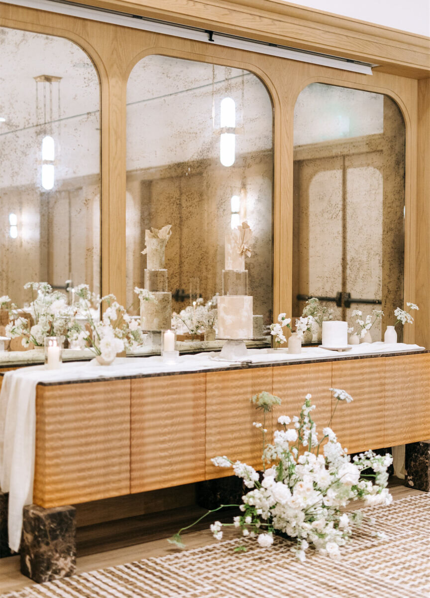 A side table holds the wedding cake, flowers, and candles, at a modern California wedding.