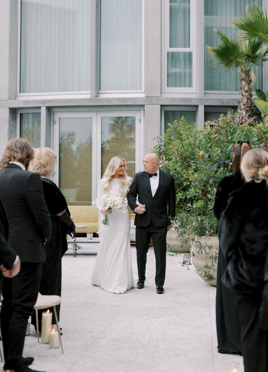 A bride and her father walk down the aisle during the ceremony of her modern California wedding.