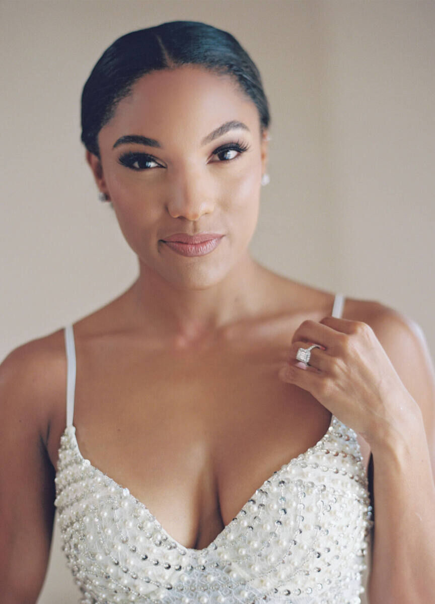 Before putting on her dress, bride Tara Davis pauses for a portrait, showing off her sleek updo and natural-but-glowy makeup.