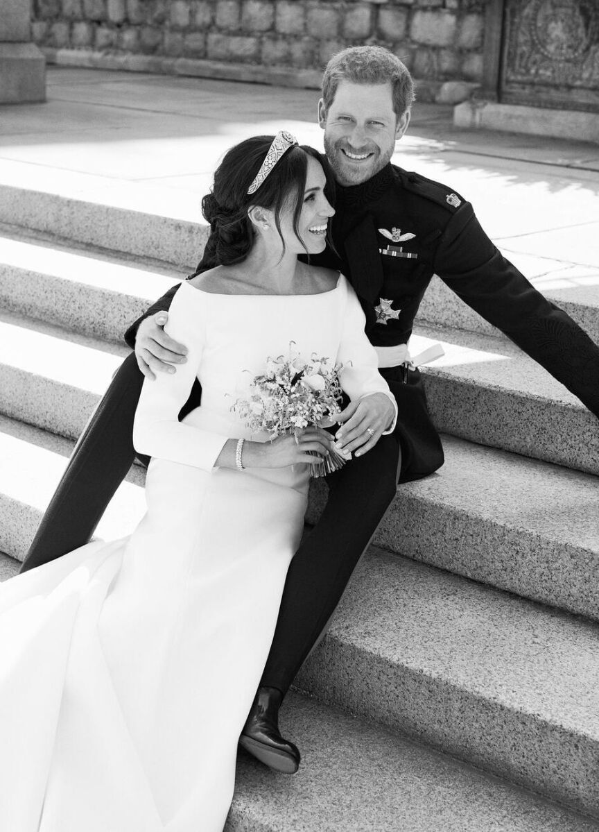 Most Influential Women in History Weddings: Meghan Markle in her wedding gown sitting with on stone steps with husband Prince Harry