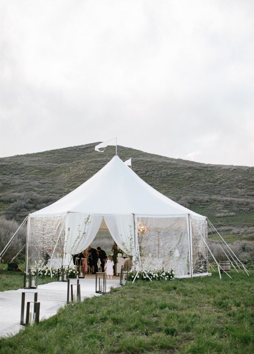 Mountain Wedding: A white tent with clear walls and a white flag on top, with a pathway leading into it and the Utah mountains in the background.