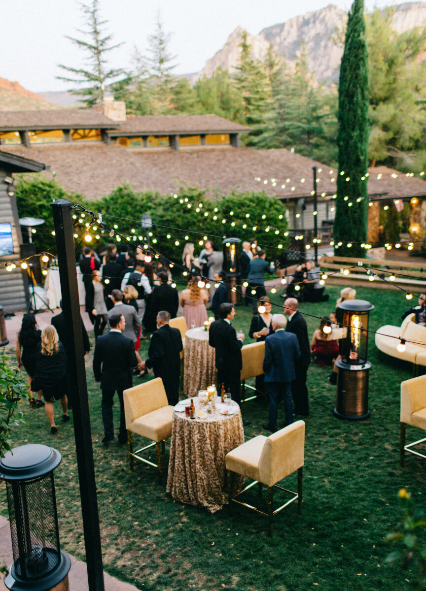 Mountain Wedding: Guests gathered outdoors during cocktail hour at a wedding in Sedona, with yellow seating and string lights in a woodsy area.