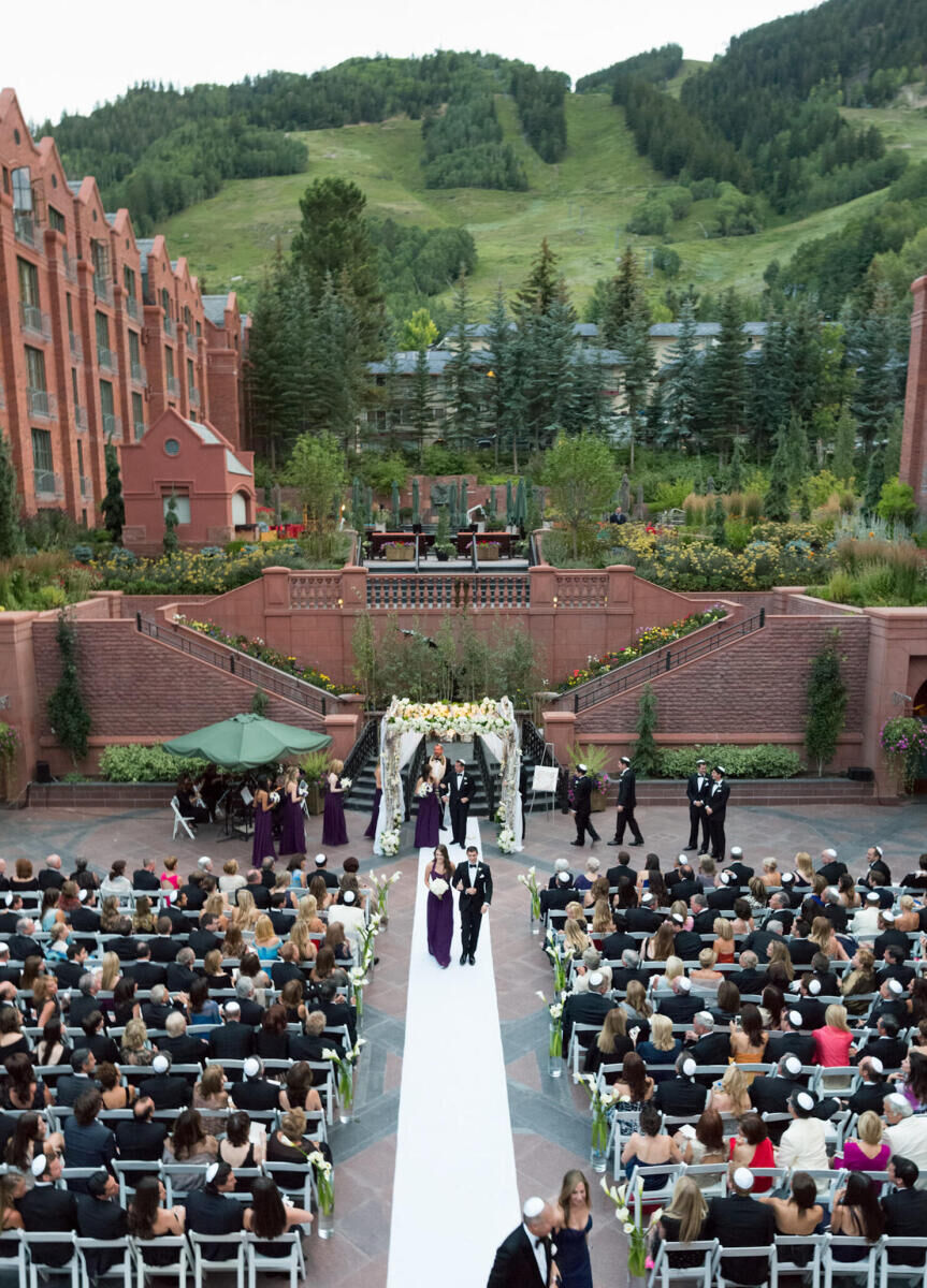 Mountain Wedding: A wedding party recessing down an aisle at an outdoor wedding ceremony at a mountain resort in Aspen, Colorado.