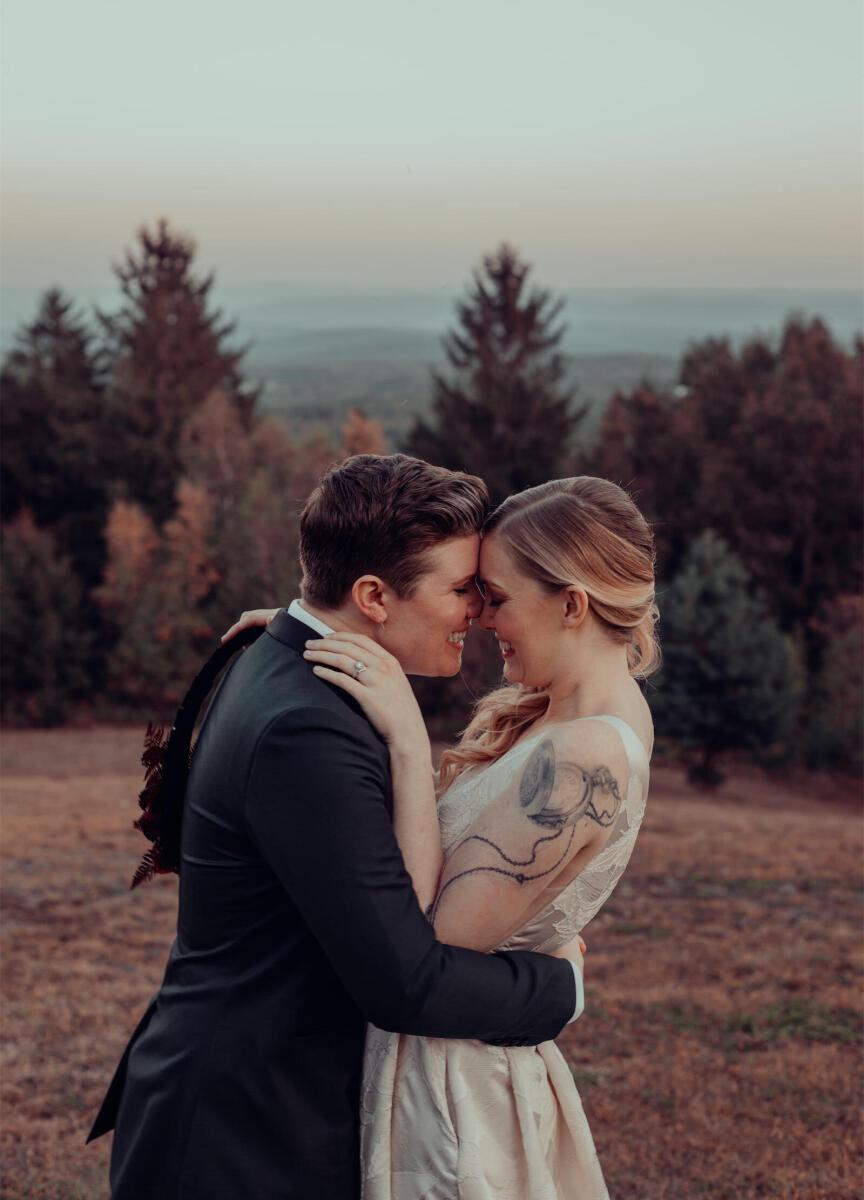 Mountain Wedding: A wedding couple embracing and smiling outdoors, with a view of trees and mountains in the background.