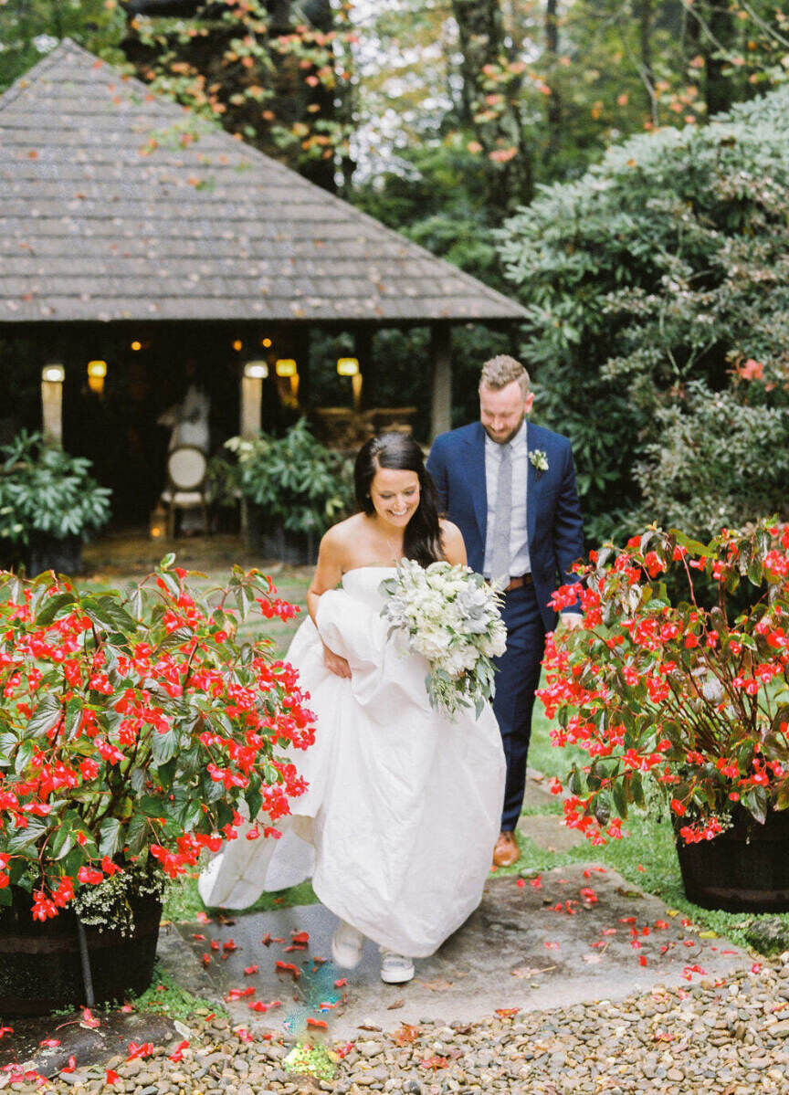 Mountain Wedding: A bride walking a step ahead of a groom on an outdoor staircase, with red flowers growing on either side, and some sort of room or overhang behind them.