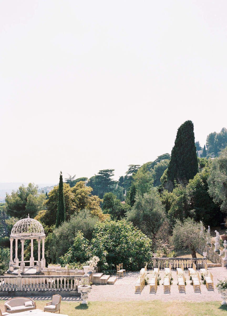 Mountain Wedding: A side view of an outdoor wedding setup on an estate in the mountains of France, featuring six rows of seating leading up to a gazebo at the altar.