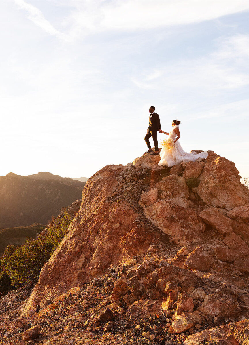 Mountain Wedding: A bride and groom holding hands on a rocky structure overlooking the mountains in Los Angeles.