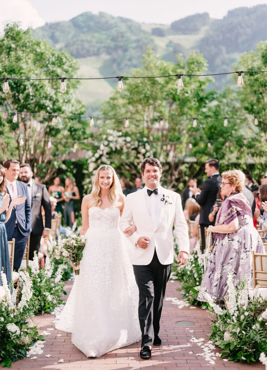 Mountain wedding details: A pair of newlyweds smile as they walk up the aisle at the end of their outdoor wedding ceremony.