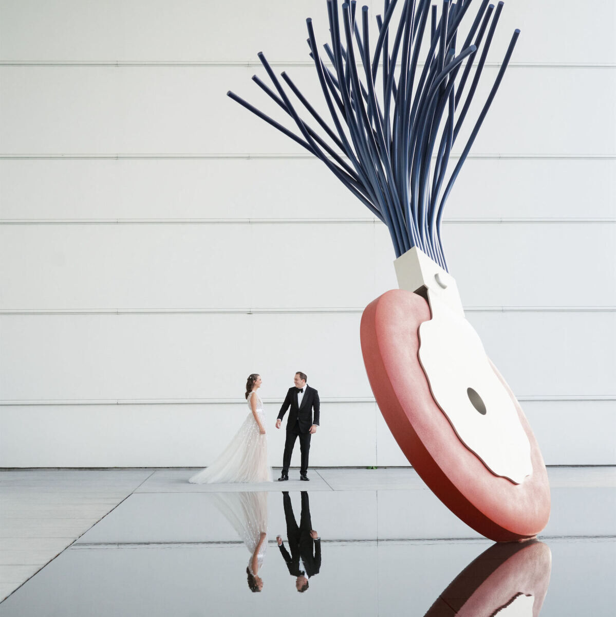 Wedding couple holding hands next to a giant sculpture in front of the Norton Museum of Art in Palm Beach, Florida.