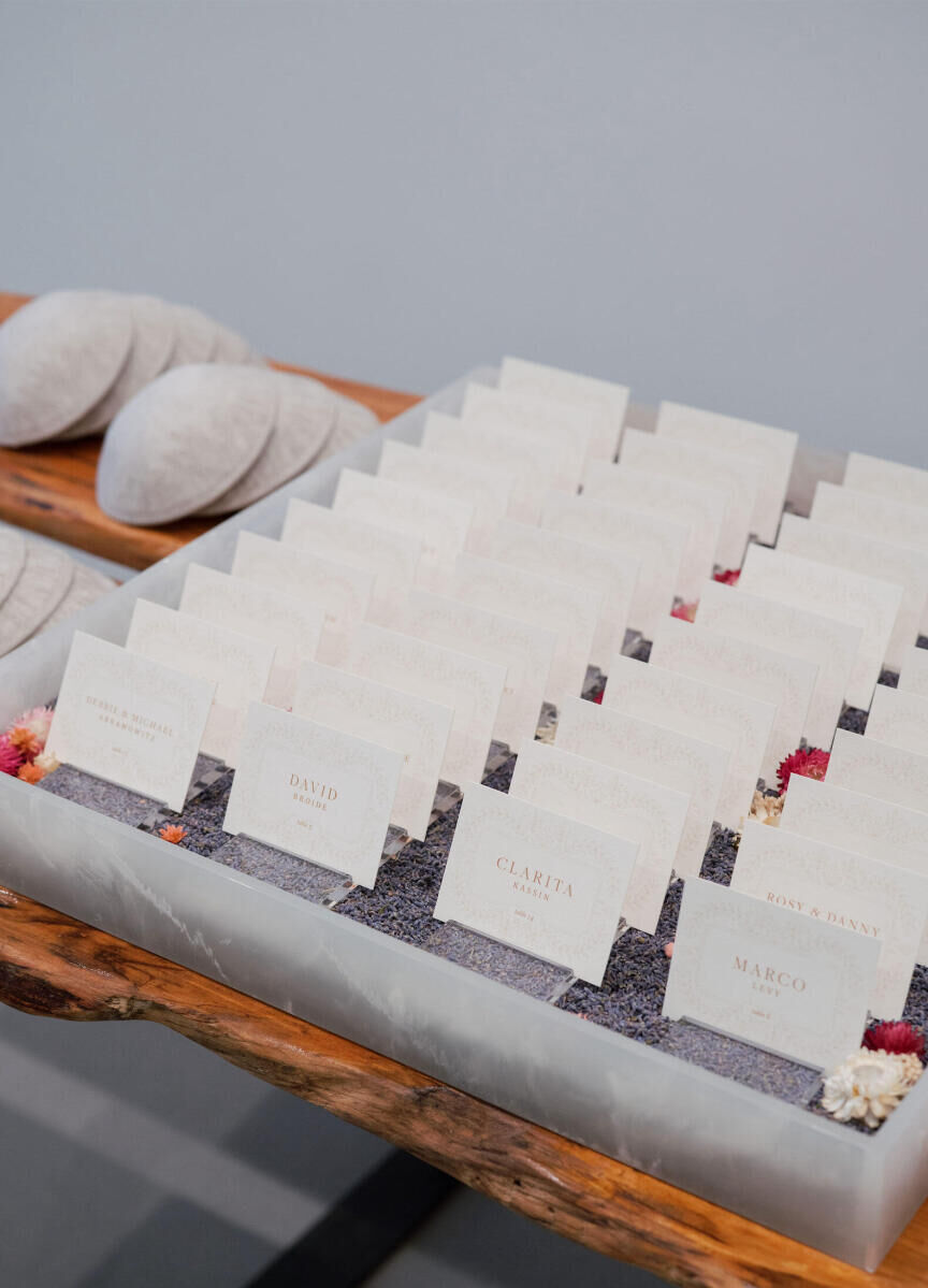 A tray of escort cards sits next to a pile of kippot at a Jewish, museum wedding.