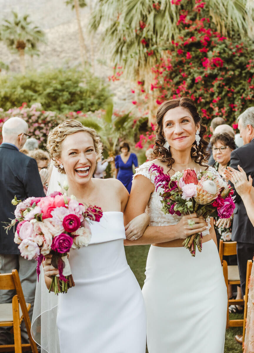 Pink Wedding: Two brides smiling while walking up the aisle after their wedding ceremony.