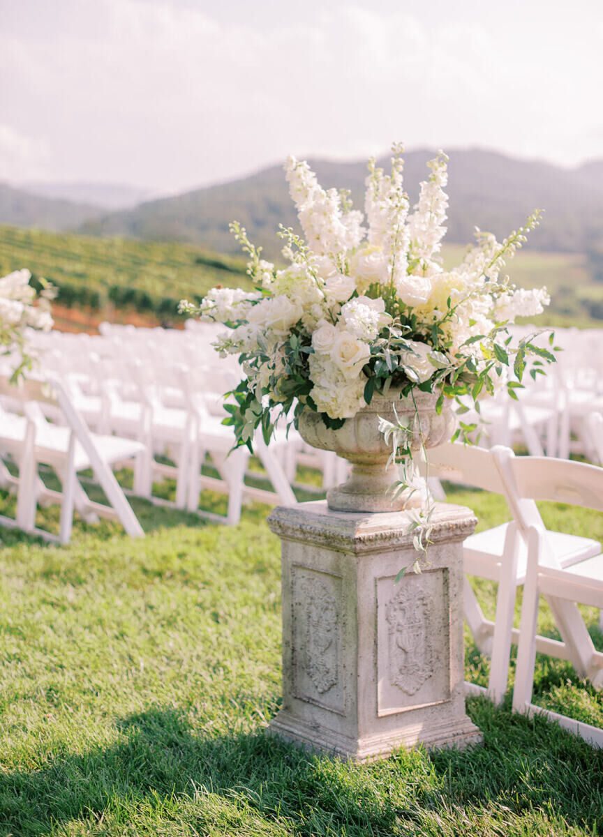 Pippin Hill Farm: A stand with an oversized floral arrangement at the beginning of a wedding aisle at an outdoor ceremony.