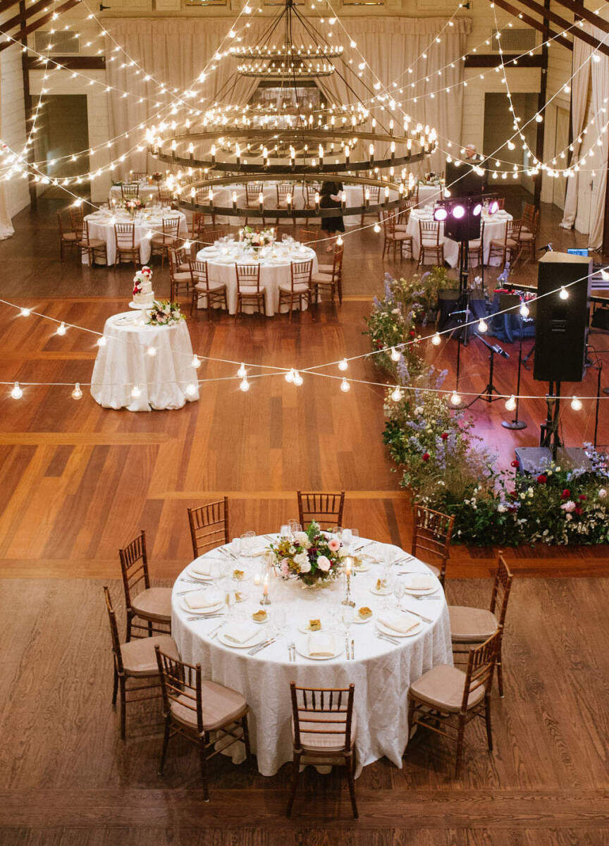 Pippin Hill Farm: An overhead view of a reception area with a stage for the band, round tables, and an oversized chandelier with string lights hung all around it.