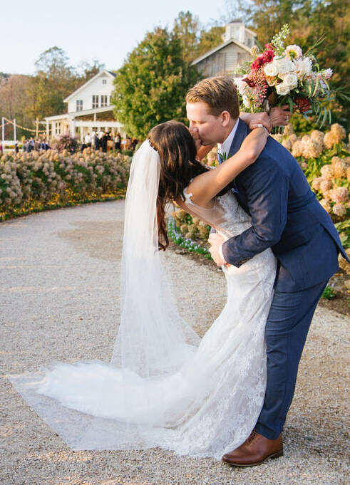 Pippin Hill Farm: A wedding couple kissing in a hydrangea-lined walkway.