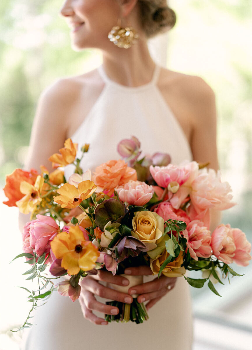 At her rainbow wedding, this bride's bouquet focused on the warm tones: pinks, oranges, yellows, and purples.