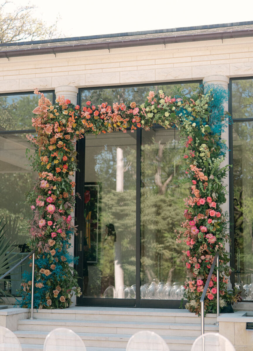 A rainbow wedding ceremony arch set around the back entrance to a modern home in Dallas.