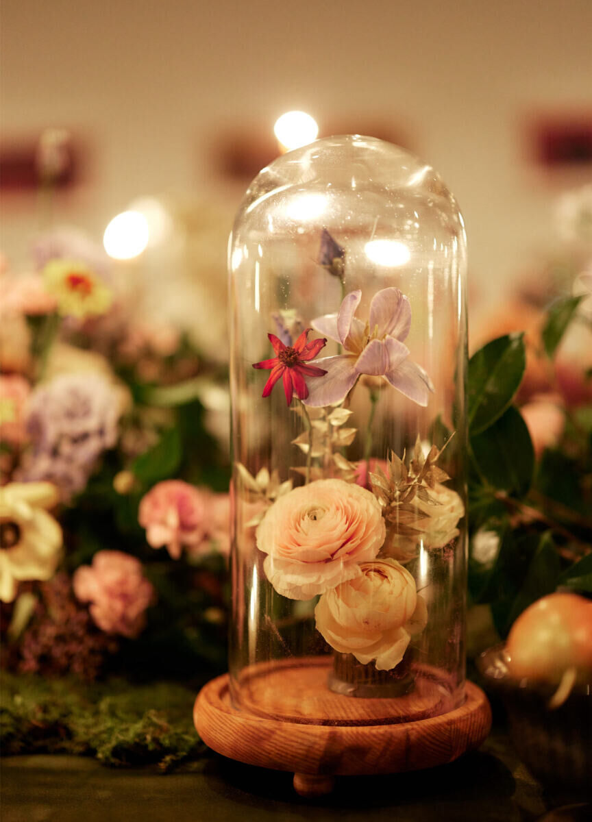 The singular table used to host all of the guests at an intimate, restaurant wedding included cloches holding fresh flowers and gilded leaves as part of the decor.