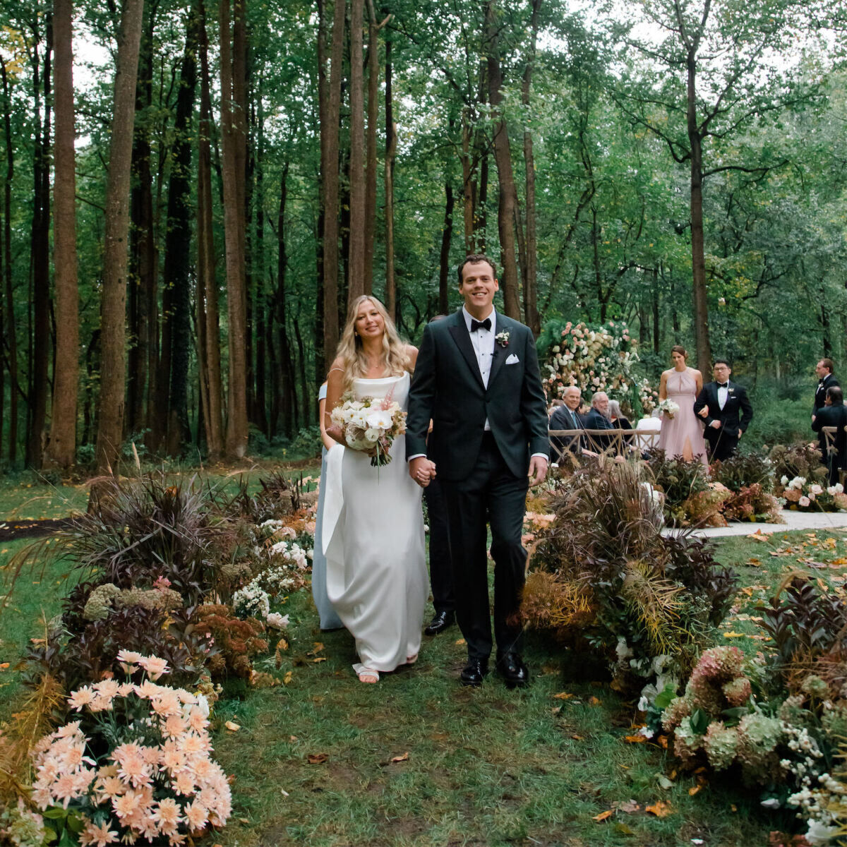 A pair of newlyweds recess up a flower-lined aisle at their rustic outdoor wedding in Virginia.