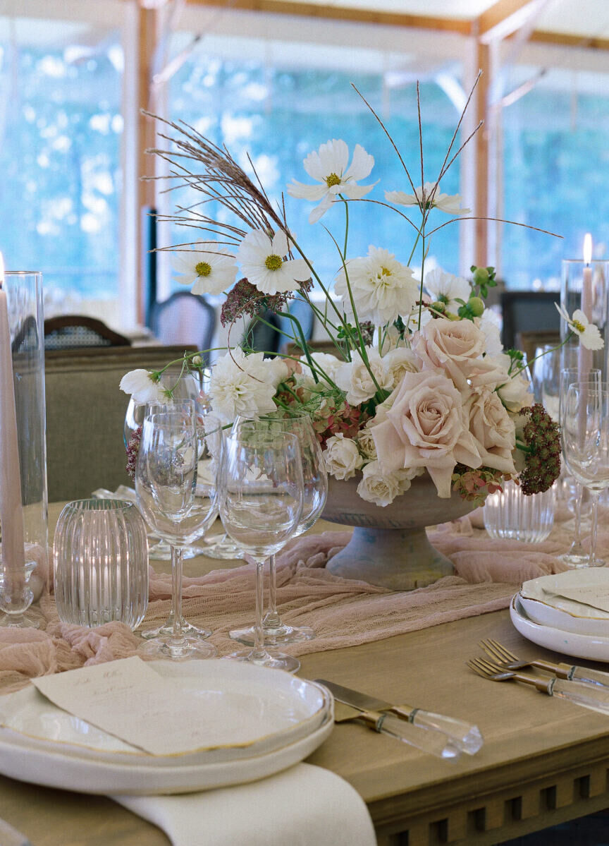 The reception tables at a rustic outdoor wedding were set with an elegant mix of rented tabletop items, like handmade plates and modern, clear-handled flatware.