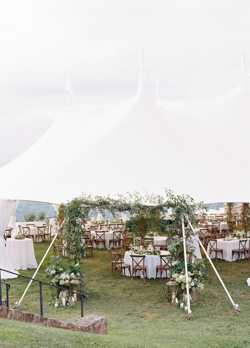 SEO for Wedding Venues: A white tented reception area with white tables, wooden chairs, and lots of greenery.