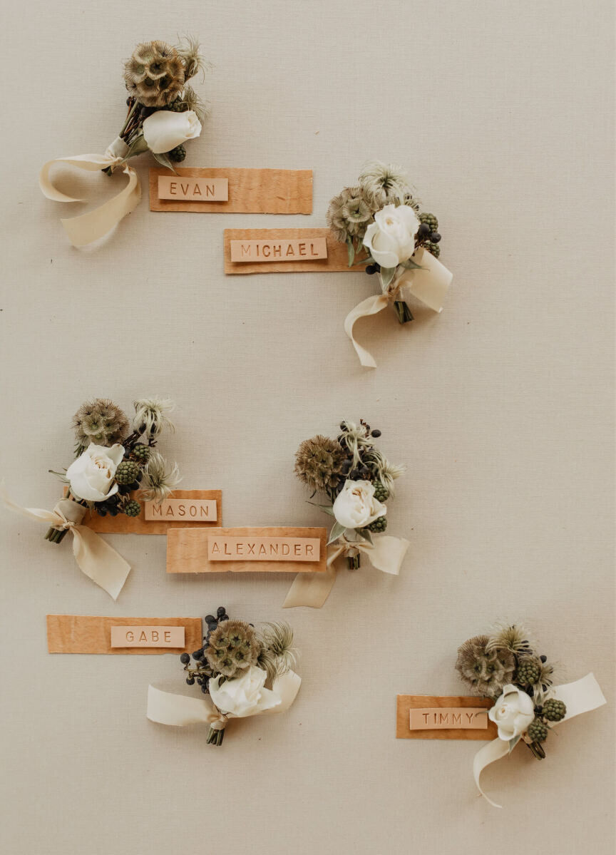 Untraditional wedding boutonnieres of spray roses, scabiosa pods, and unripe raspberries.