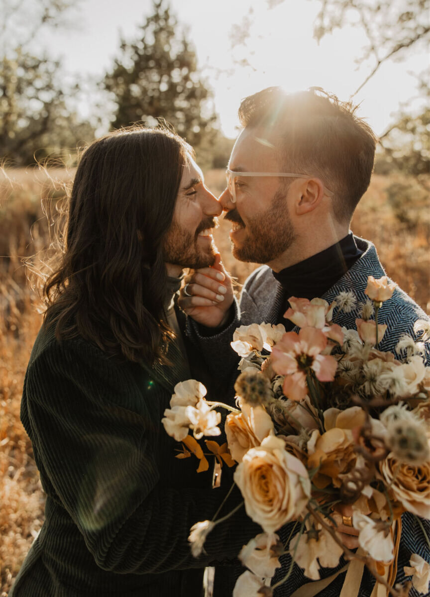 A close-up portrait of two grooms with the sun glowing behind them in the Texas countryside.