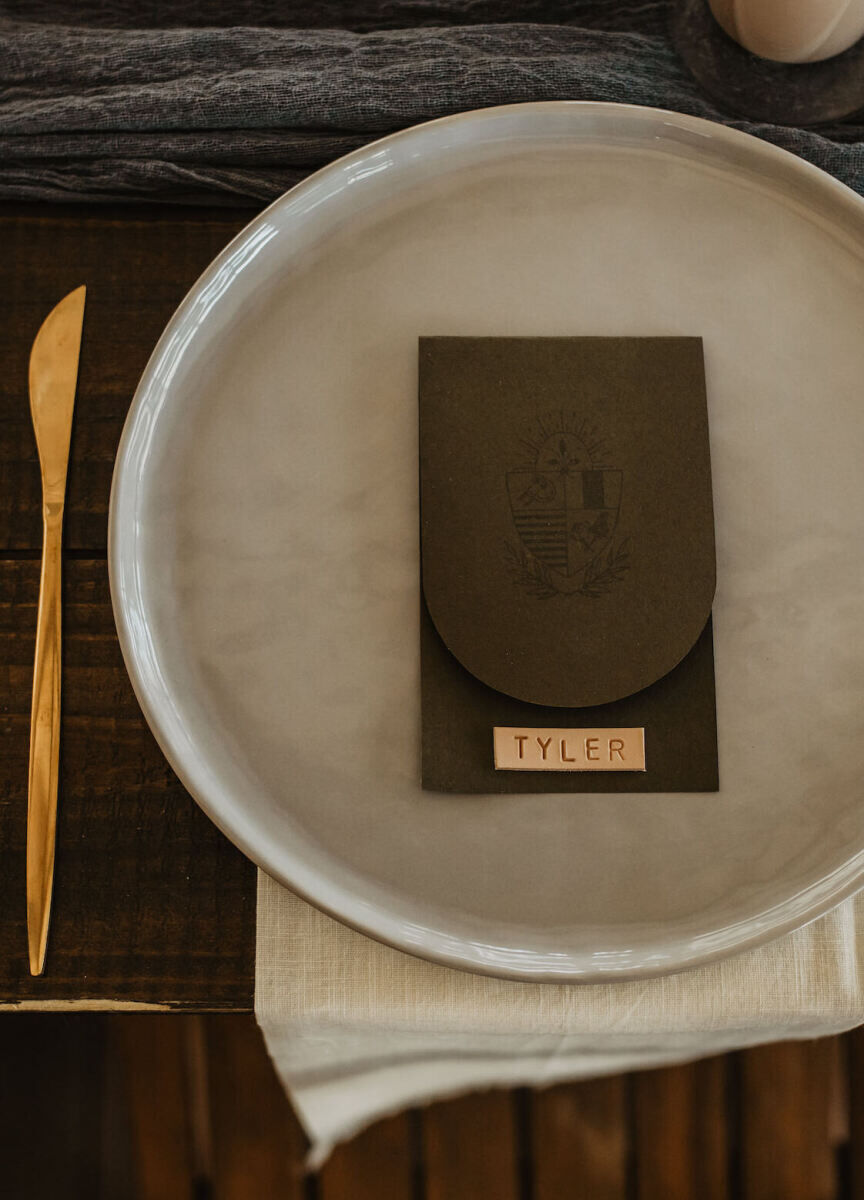 Leather place cards and rounded green envelopes holding notes to each guest were the finishing touches on these modern place settings at an untraditional wedding.