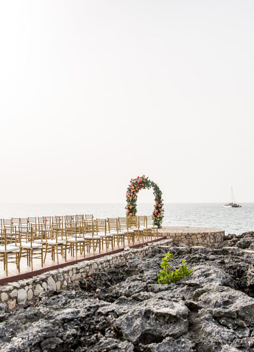 Wedding Aisle: An aisle on a rocky path leading up to the ocean with a sailboat in the background.