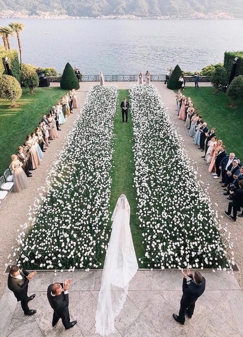 Wedding Aisle: A bride walking down a grassy area with white flowers creating the aisle.