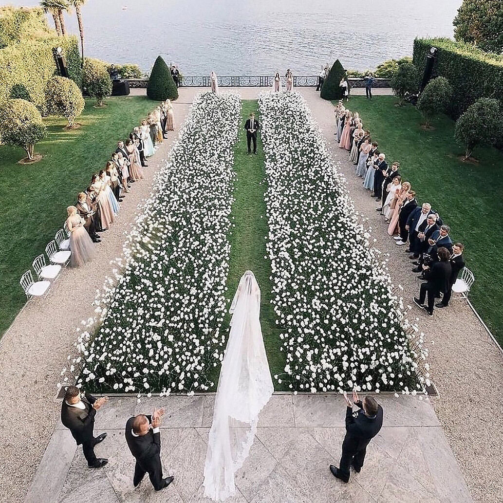 Wedding Aisle: A bride walking down a grassy area with white flowers creating the aisle.