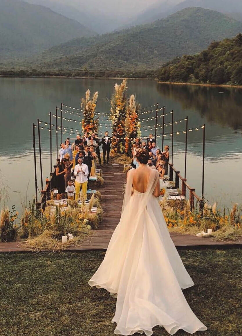 Wedding Aisle: A bride walking onto a dock on the water, overlooking the mountains in Georgia beyond.